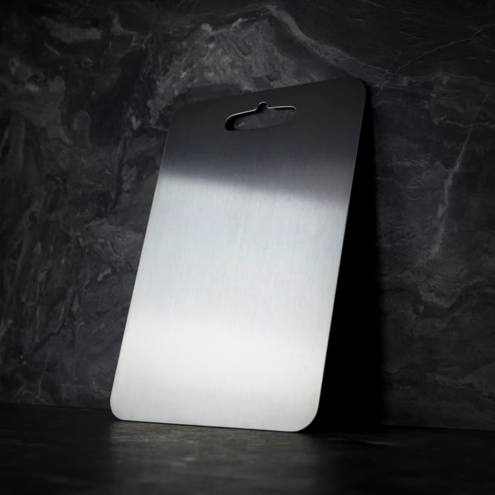 Brushed silver titanium chopping board with rounded corners and integrated handle opening
