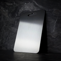Brushed silver titanium chopping board with rounded corners and integrated handle opening