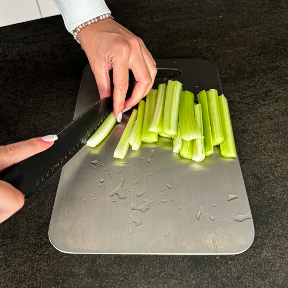Brushed silver titanium chopping board with rounded corners and integrated handle opening