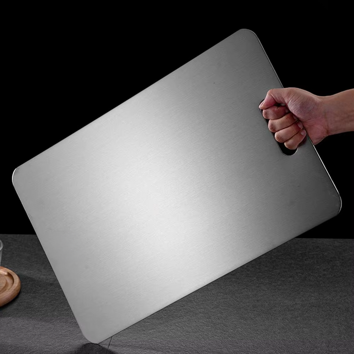 Brushed silver titanium chopping board with rounded corners and integrated handle opening
