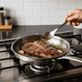 Silver uncoated titanium frying pan with long handle on a hob