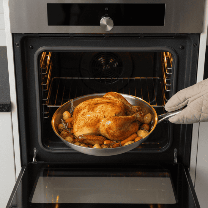 Silver uncoated titanium frying pan with long handle on a hob
