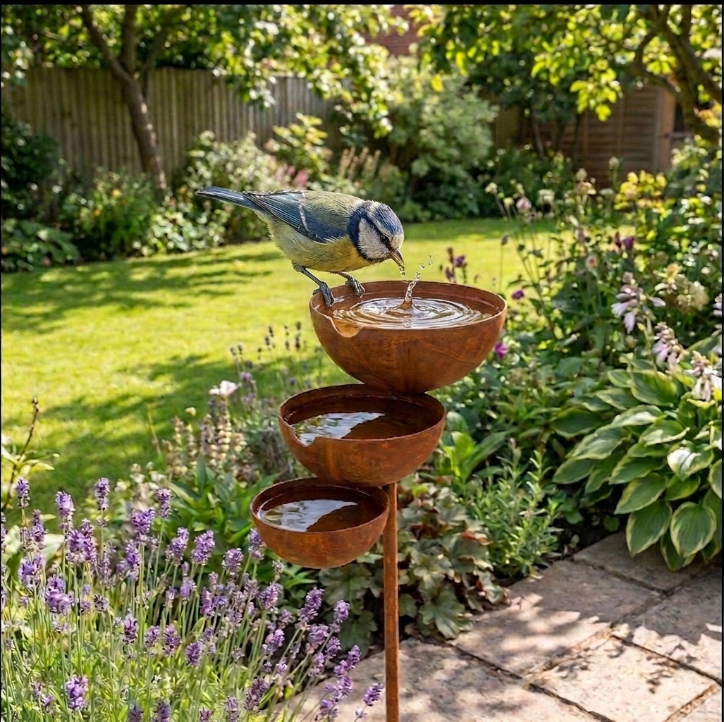 Three-tier brown bird bath with three bowls on a garden stake