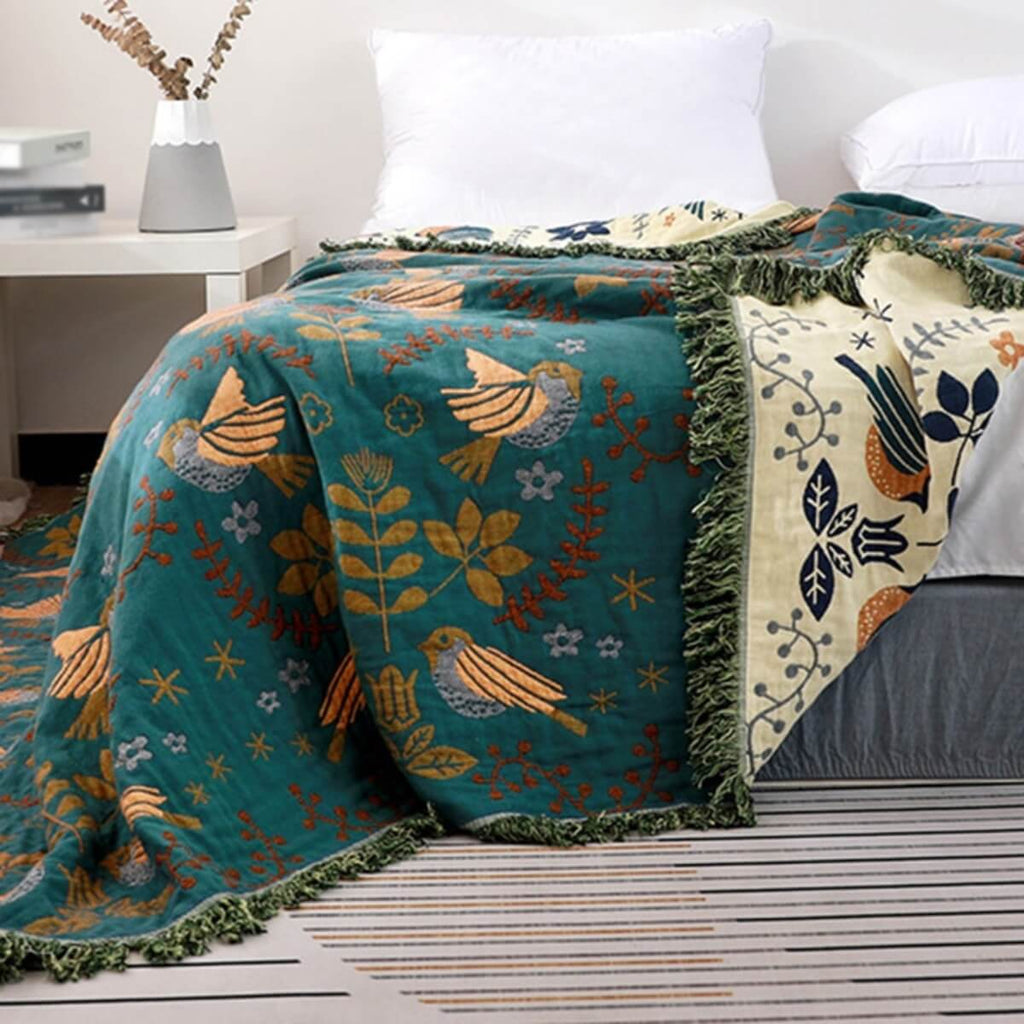 Reversible botanical patterned blanket with contrasting bird design and fringed edges
