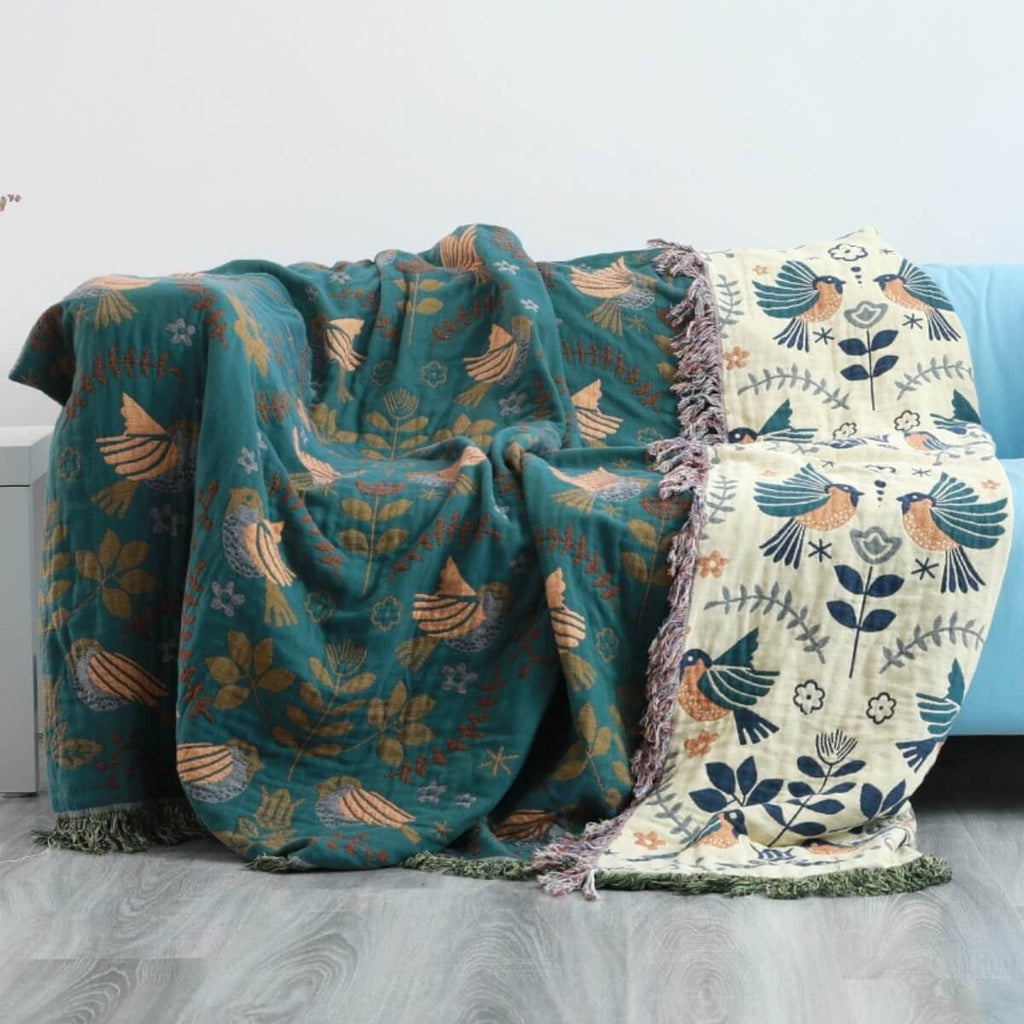 Reversible botanical patterned blanket with contrasting bird design and fringed edges