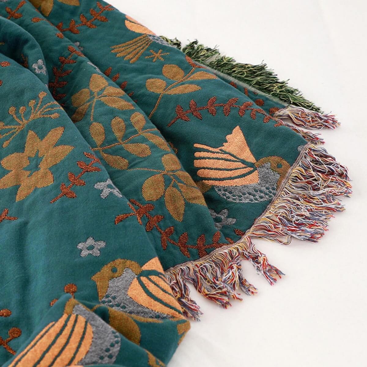 Reversible botanical patterned blanket with contrasting bird design and fringed edges