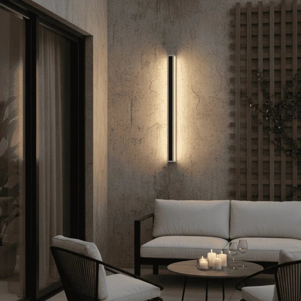 Slim black vertical outdoor wall light casting a warm glow