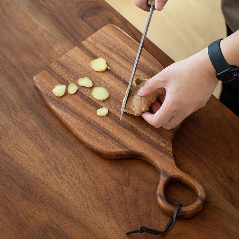 Brown walnut cutting board with shaped handle and rounded hanging hole